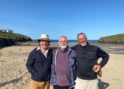 three happy men in casual clothing on a beach