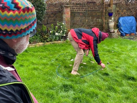 man on green lawn placing small stones